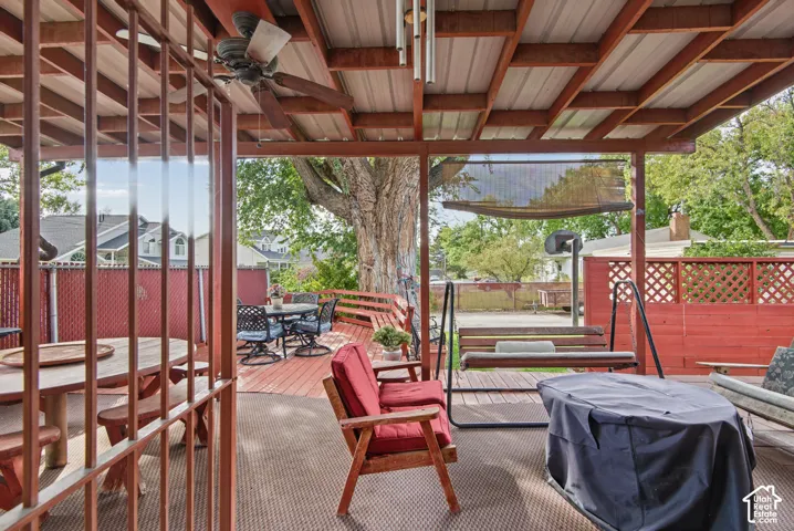 Covered patio with a corrugated metal roof, ceiling fan, and wood framing