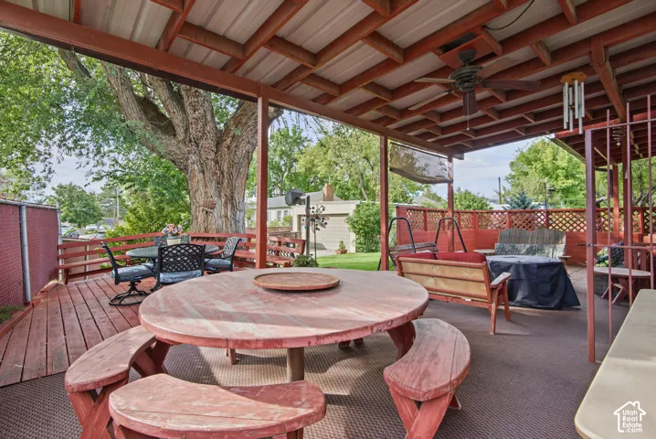 Expansive covered deck featuring a ceiling fan, wood railing, and privacy lattice