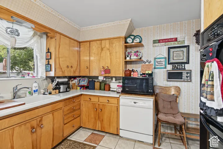 Wood-finish cabinetry with silver-tone hardware, white countertop surfaces, and a white drop-in sink