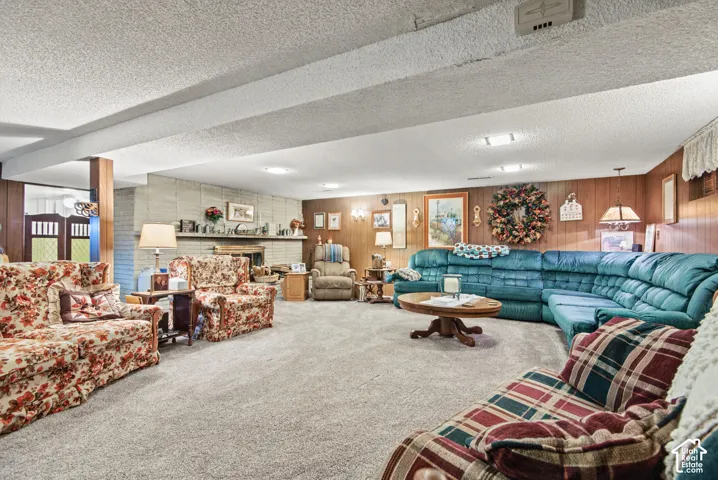 Carpeted living area featuring a brick fireplace, wood-paneled walls, and recessed lighting