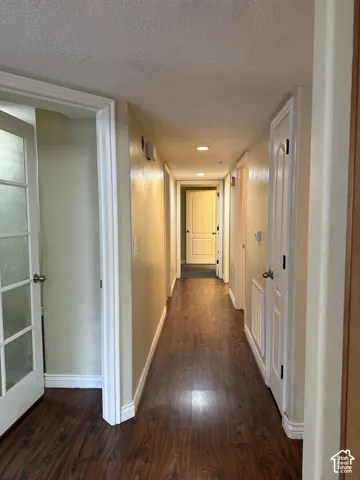 Hallway featuring wood-finish flooring, recessed ceiling lighting, and multi-panel interior doors, including a French door with glass panes