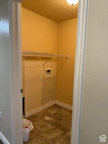 Utility space featuring ceramic tile flooring, built-in wire shelving, and dedicated washer and dryer hookups