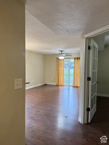 Wood-finish flooring, ceiling fan with integrated lighting, and glass sliding doors featuring a rail-style entry