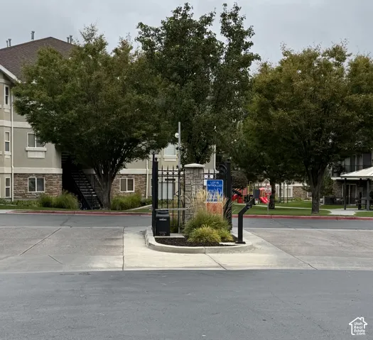 Gated community entrance featuring stone-pillar accents, metal perimeter fencing, and mature landscaping