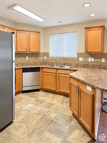 Kitchen featuring wood cabinetry, laminate countertops, mosaic tile backsplash, tile flooring, and integrated stainless steel dishwasher