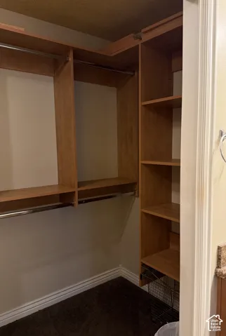 Walk-in closet featuring wood-finish shelving, integrated hanging rods, and built-in vertical storage towers