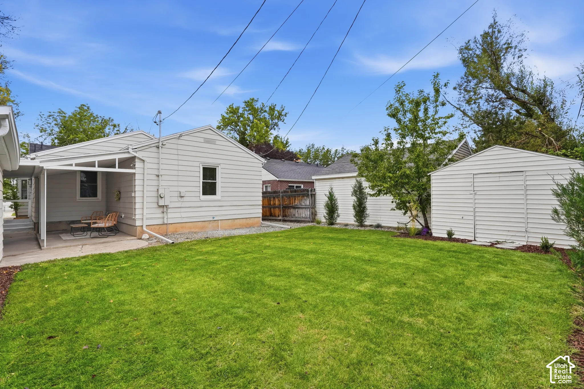 Expansive lawn area with a covered patio, a detached storage shed, and a privacy fence