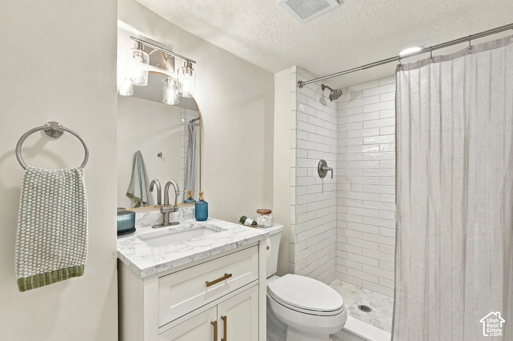 Bathroom #2 with white subway tile, quartz countertops, & marble flooring.
