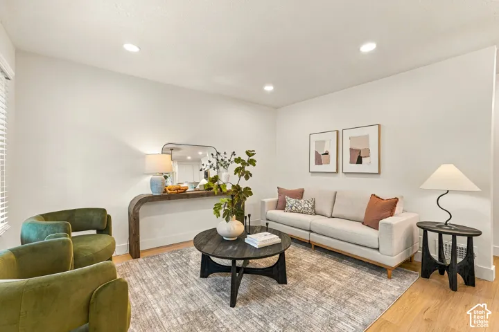 Recessed ceiling lighting, light wood-finish flooring, white walls, console table with integrated mirror, and window with blinds