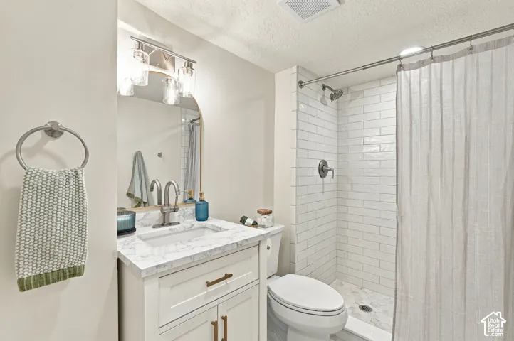 Bathroom #2 with white subway tile, quartz countertops, & marble flooring.