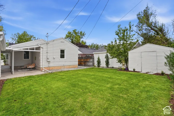 Expansive lawn area with a covered patio, a detached storage shed, and a privacy fence