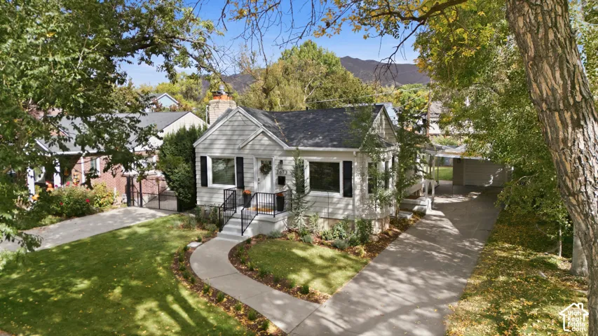 Light-colored siding exterior with dark shutters, dark roof, and a front porch