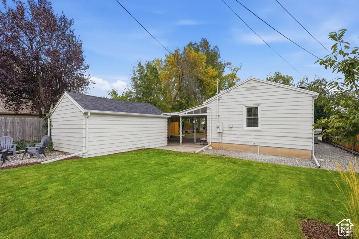 Expansive green lawn, detached outbuilding, covered patio, gravel landscaping, and mature trees