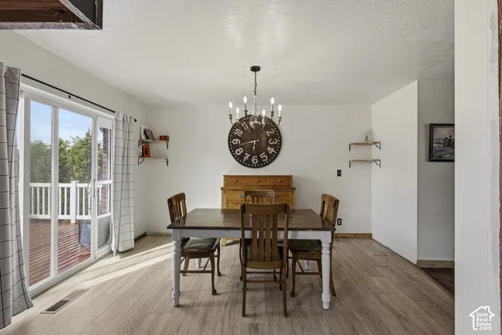 Sliding glass door, wood-finish flooring, and multi-arm chandelier lighting