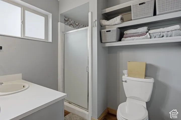 Bathroom featuring an integrated vanity with a circular sink, a glass-enclosed shower, and built-in wall shelving
