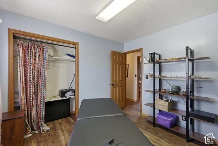 Room featuring wood-finish flooring, a six-panel wood door, and a built-in closet with overhead shelving