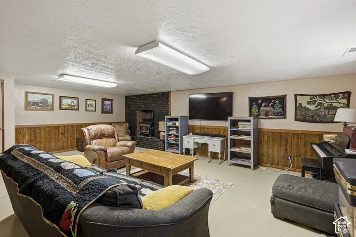 Brick fireplace with an integrated wood-burning stove insert, wood-finish wall paneling, and dual rectangular overhead light fixtures