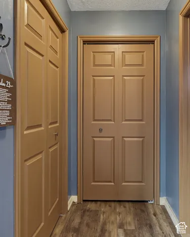 Hallway featuring wood-finish flooring and two four-panel bi-fold doors with wood trim