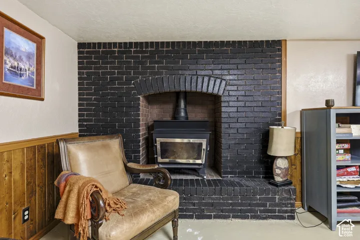 Floor-to-ceiling dark brick fireplace surround featuring an arched masonry detail, a raised brick hearth, and a freestanding wood-burning stove insert