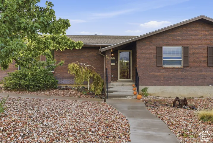 Ranch-style brick exterior featuring a covered entryway, concrete walkway, and decorative window shutters