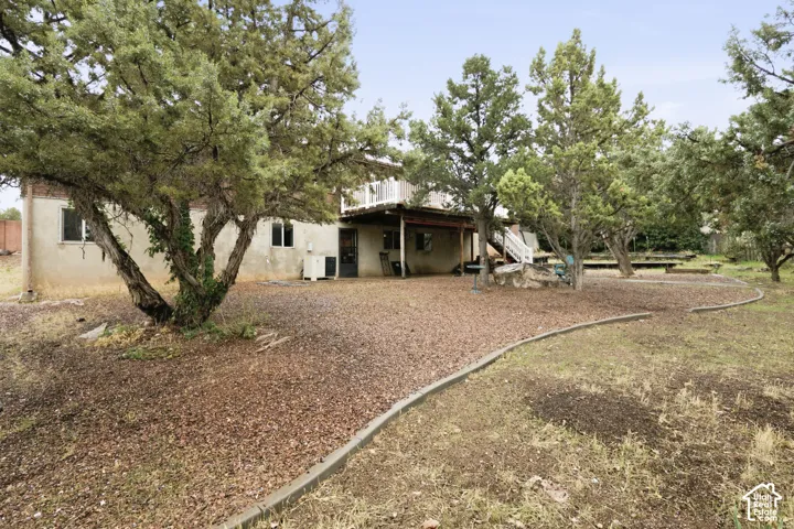 Backyard area featuring an expansive gravel ground cover, mature trees, a ground-level covered patio, and a tiered exterior deck