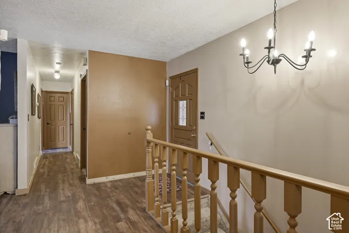 Entryway featuring wood-finish flooring, a traditional six-light chandelier, a solid-wood front door with a decorative glass insert, and a matching wood stair railing