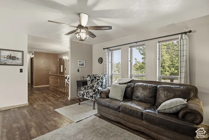 Wood-finish flooring, multi-pane windows, ceiling fan with integrated lighting, and wooden staircase railing