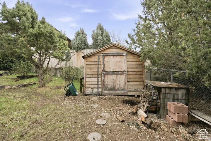 Outdoor storage shed with horizontal wood siding, gravel ground cover, and mature evergreen trees