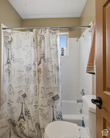 Bathroom featuring a white tile surround tub enclosure, stainless steel shower fixtures, built-in window, and a solid wood door with black hardware