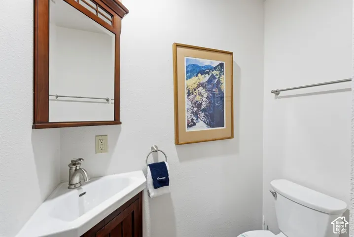 Corner pedestal sink with a brushed nickel faucet, wood-finish mirror, and white toilet
