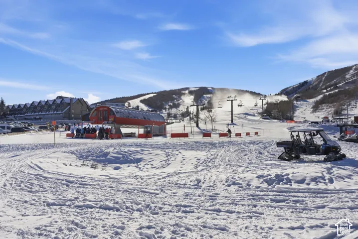 Mountain terrain featuring a ski lift terminal, groomed slopes, and multi-story lodge architecture