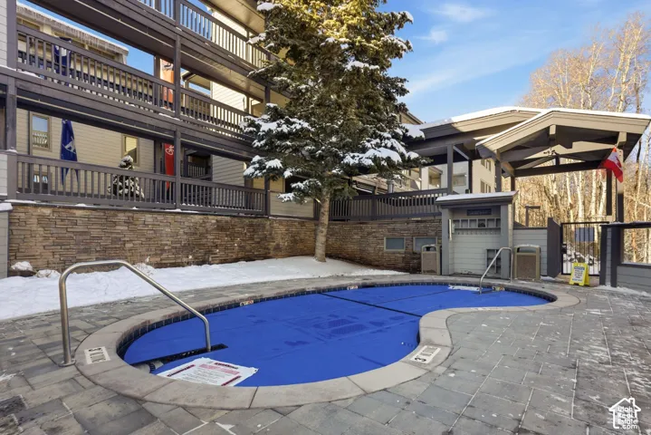 Outdoor spa with stone retaining wall, stone paver decking, and metal handrails