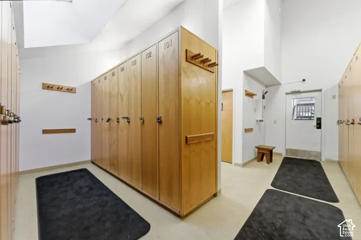 Storage area featuring floor-to-ceiling wood-finish lockers with integrated numbering and mounted coat hooks