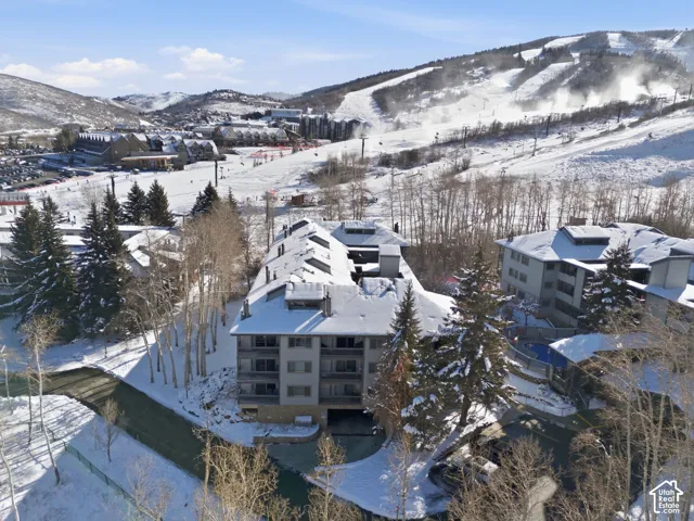 Multi-story residential structure with multiple balconies, situated amidst a snowy landscape with mature trees