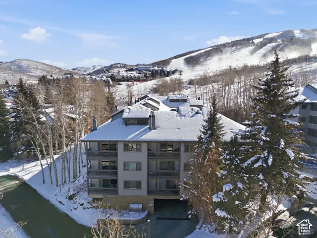Multi-story building with a snow-covered roof, multiple balconies, and a stone-clad base