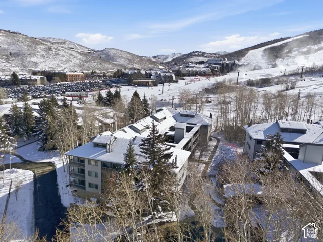 Multi-story exterior featuring stone and stucco siding, metal roof accents, multiple private balconies, and proximity to mountain slopes