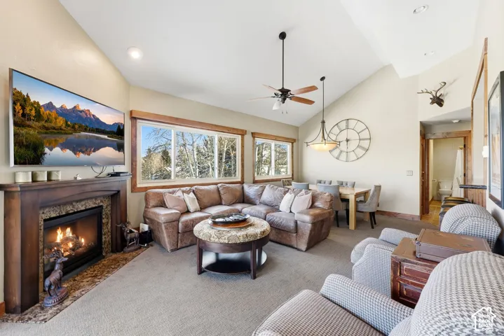 Spacious living area featuring a vaulted ceiling, wood-finish mantel and fireplace with stone surround, large windows, and recessed lighting