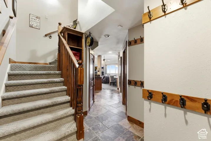 Carpeted staircase with wood-finish railing, built-in shelving, and tile flooring