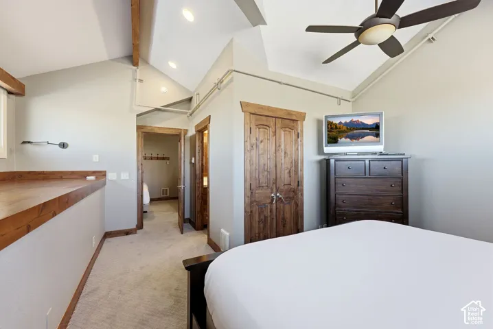 Vaulted ceiling with exposed wood beam, recessed lighting, ceiling fan, carpeted flooring, and wood-trim double-door closet