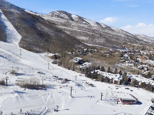 Aerial perspective featuring expansive mountain terrain, groomed snow-covered slopes, and mature evergreen and aspen clusters