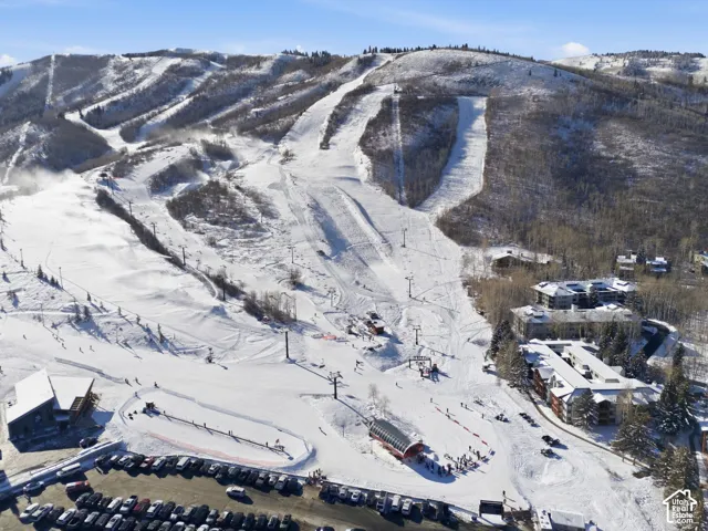 Expansive snow-covered mountain terrain featuring multiple ski slopes, a ski lift system, and various alpine trees