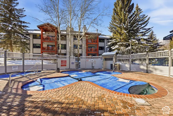 Outdoor spa featuring a multi-sectioned pool, brick paver decking, privacy lattice fencing, and metal handrails