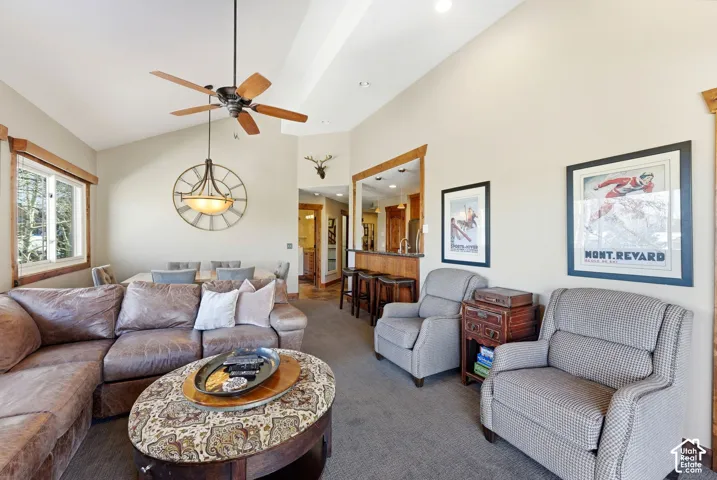 Vaulted ceilings, recessed lighting, and a prominent ceiling fan with wood-finish blades