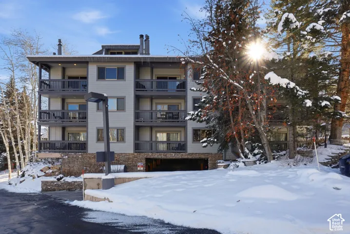 Multi-story exterior featuring stone veneer foundation, horizontal siding, private balconies, and integrated parking garage