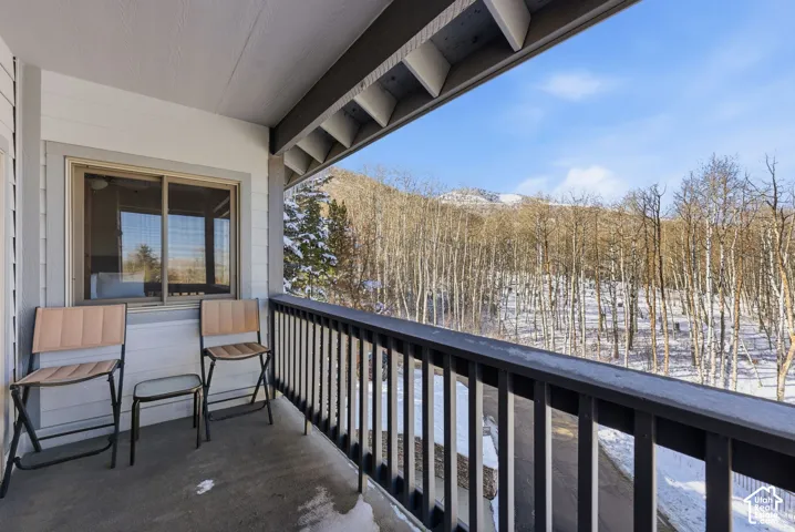 Covered outdoor balcony with a black railing, featuring a sliding window entry