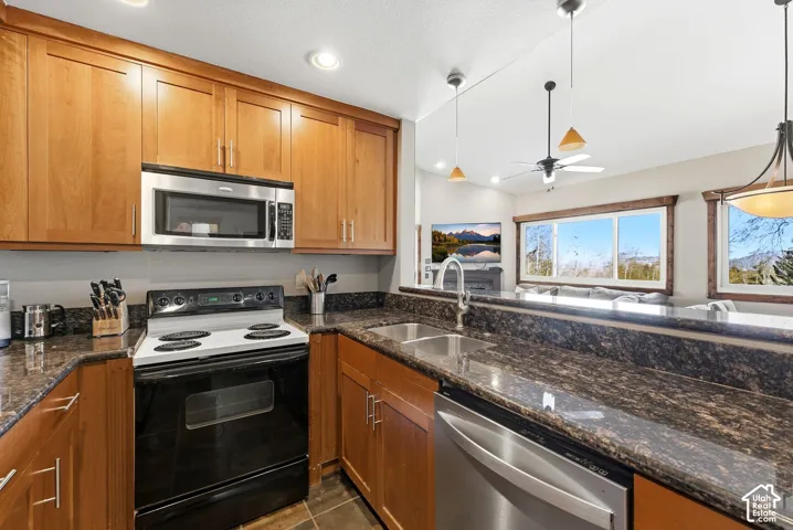 Kitchen featuring wood cabinetry, dark speckled countertops, and stainless steel appliances