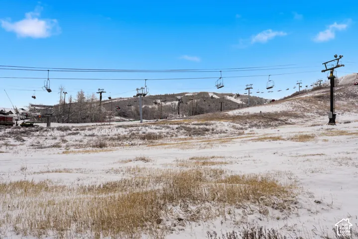 Snow-covered landscape featuring multiple ski lift lines and a distant mountain range