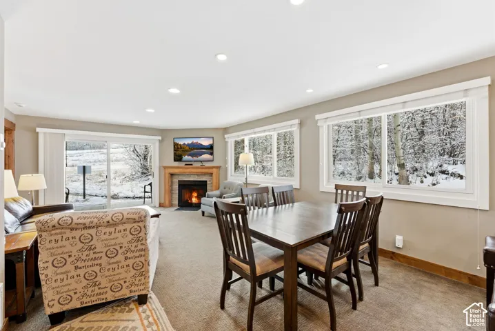 Open-concept living space featuring recessed lighting, a stone-surround fireplace with wood mantel, and a sliding glass door