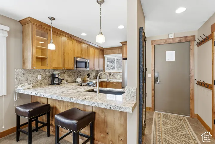 Kitchen featuring wood cabinetry, stainless steel appliances, and stone-finish countertops