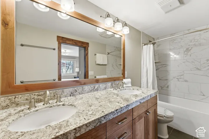 Dual vanity with granite countertop, wood-finish cabinetry, and brushed nickel fixtures